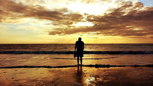 Silhouette of people on beach at sunset