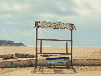 Lifeguard chair on beach against sky