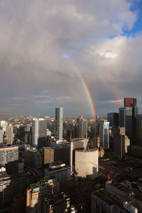 Rainbow over city buildings against sky