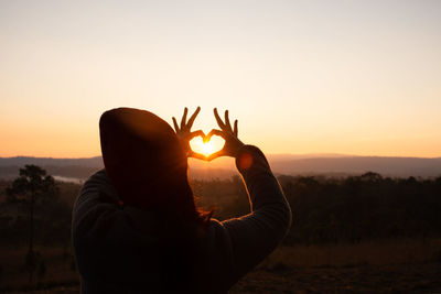 Silhouette man in sunlight against sky during sunset