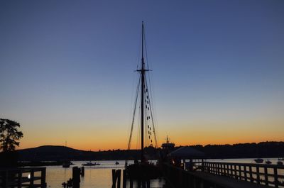Sailboats moored on shore against clear sky during sunset