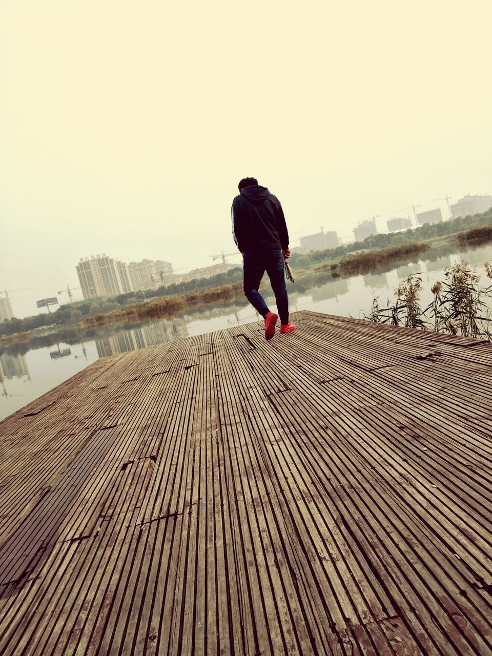 FULL LENGTH REAR VIEW OF MAN WALKING ON ROAD AGAINST CLEAR SKY