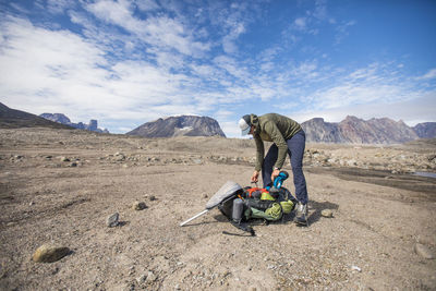 Man with umbrella on mountain against sky