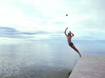 Full length of man jumping in sea against sky