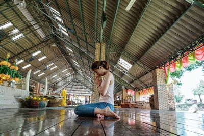 Full length of young woman sitting on ceiling