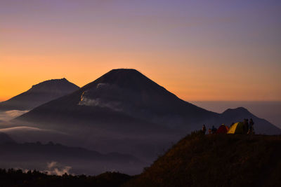 Scenic view of silhouette mountains against orange sky