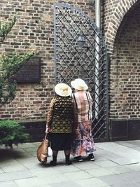 Rear view of couple standing against brick wall