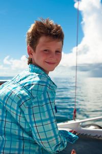 Portrait of smiling boy standing against blue sea