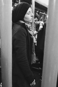 Side view of young woman standing in bus