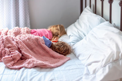 High angle view of cute kids sleeping on bed