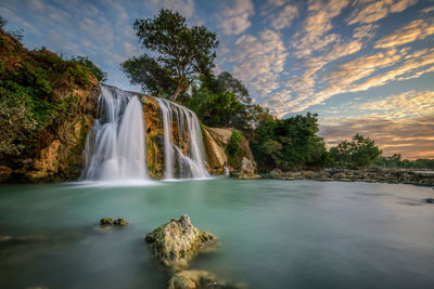 Scenic view of waterfall against sky during sunset