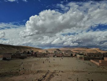 People playing soccer against cloudy sky