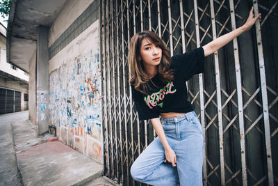 Young woman standing against graffiti wall