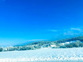 Scenic view of snow covered land against blue sky