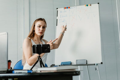 Woman teaching over whiteboard during online class