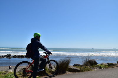 Man riding bicycle on beach against clear sky