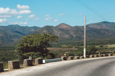 Road by trees and mountains against sky