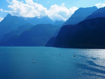 Scenic view of sea by mountains against sky