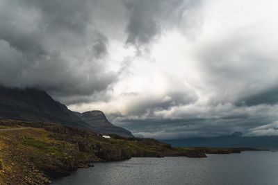 Scenic view of sea and mountains against cloudy sky