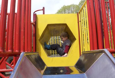 Side view full length of playful boy in play equipment at park