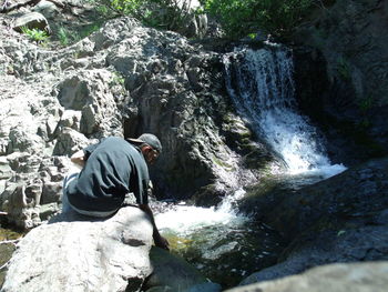 Rear view of man on rock by river