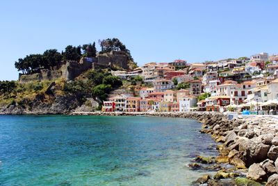 Buildings by sea against clear sky