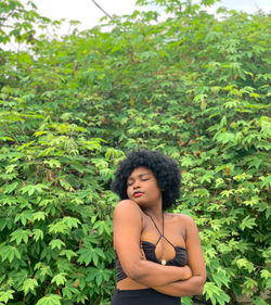 Portrait of young woman standing against plants