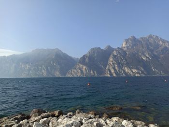 Scenic view of sea and mountains against blue sky