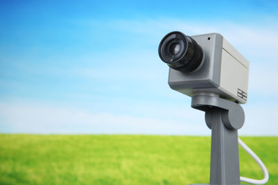 Close-up of security camera against sky