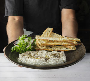 Italian cheese stracciatella -buffalo mozzarella- on a black plate served with fresh arugula