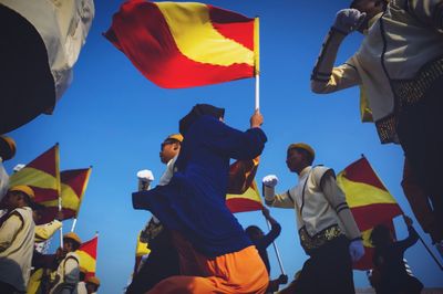 Low angle view of woman standing against blue sky