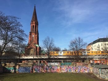 Graffiti on wall in front of church tower against railway bridge