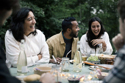 Young man enjoying with female friends during dinner party in back yard