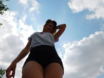 Low angle view of young woman against sky
