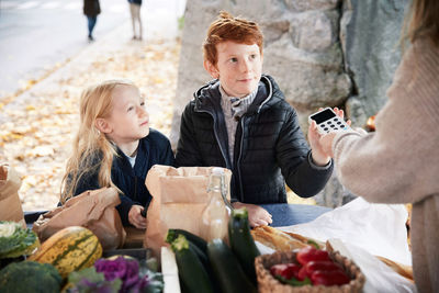 Male and female sibling with credit card reader at market stall