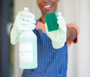 Midsection of woman holding bottle against white background