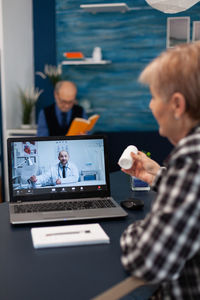 Man and woman using smart phone while sitting on table