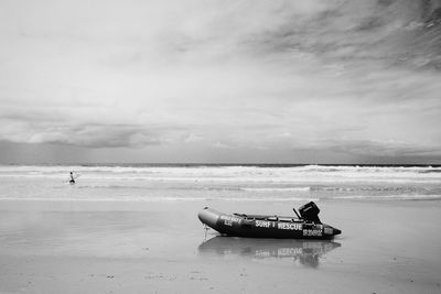 Lifeboat on beach against cloudy sky