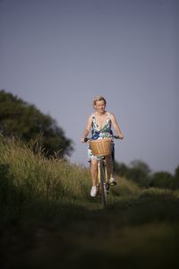 Full length of woman standing on grassy field against clear sky