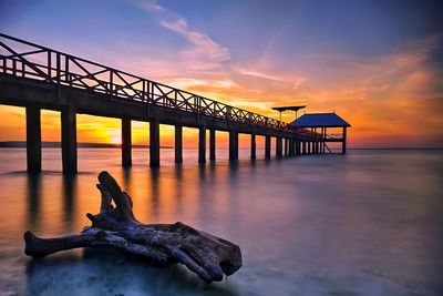 Pier over sea against sky during sunset