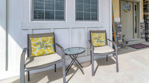 Empty chairs and table against building