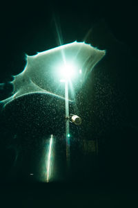 Illuminated street light against sky at night