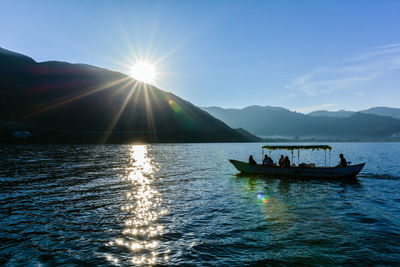 People on boat at lake against sky