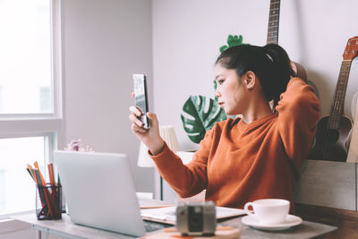 Woman using mobile phone while sitting on table