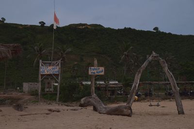 Sign board on sand against sky