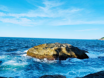 Rocks in sea against blue sky