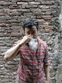 Portrait of young man standing against wall