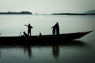 Silhouette men on boat against clear sky