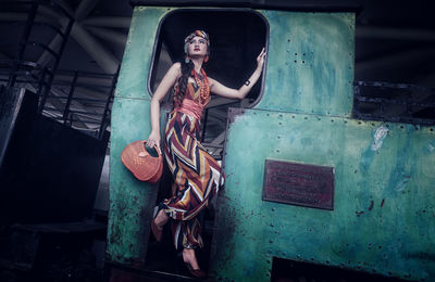 Full length of woman sitting on abandoned metal