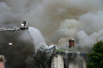 Firefighter spraying water on burnt building